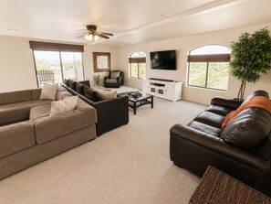 A living room with a sectional sofa, a leather couch, a TV, and a ceiling fan. - The Prescott Social + Near Whiskey Row + Views (Prescott)