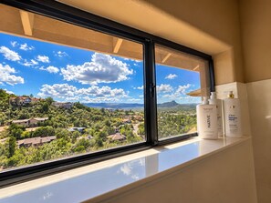Une fenêtre donnant sur un quartier résidentiel, avec deux flacons de gel douche Dove Intensive Repair posés sur le rebord de la fenêtre.