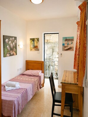Une chambre à coucher avec un lit, un bureau et une chaise. Les murs sont ornés de tableaux et il y a une fenêtre avec vue.