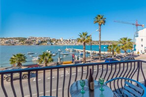 Un balcon offrant une vue sur un port de plaisance, des palmiers et le paysage urbain au loin.