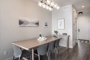 A modern kitchen with a wooden table, chairs, and a wine bottle. - 3BR Kelowna townhome with lakeview, mountain views, deck, BBQ, Wi-Fi, and parking. (Kelowna)