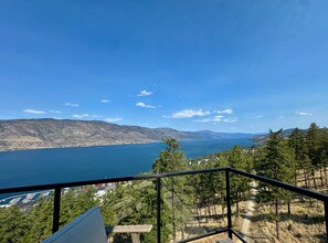 A balcony with a view of a lake, mountains, and a forested area. - 3BR Kelowna townhome with lakeview, mountain views, deck, BBQ, Wi-Fi, and parking. (Kelowna)
