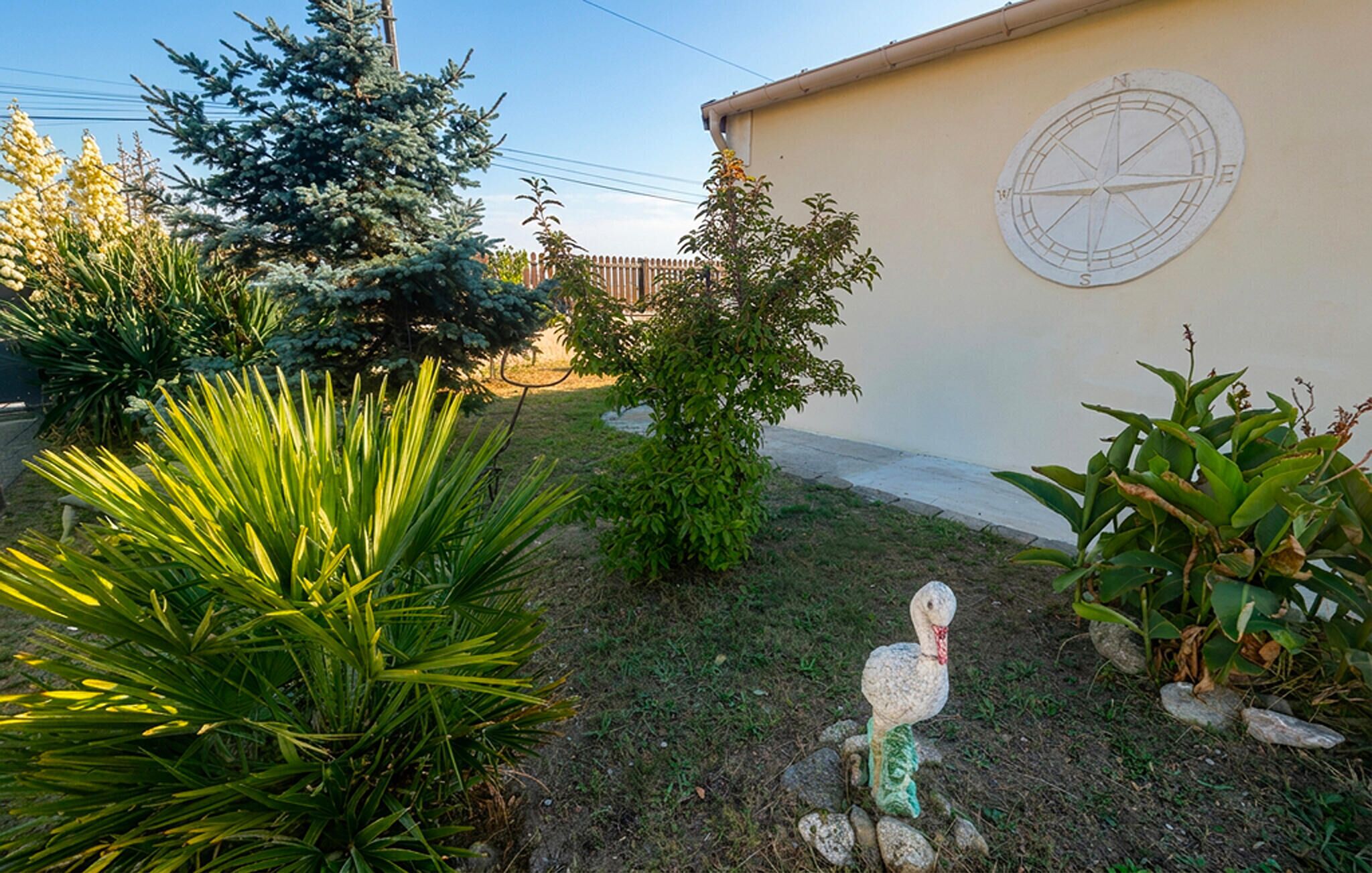 A garden with various plants and a decorative bird statue.