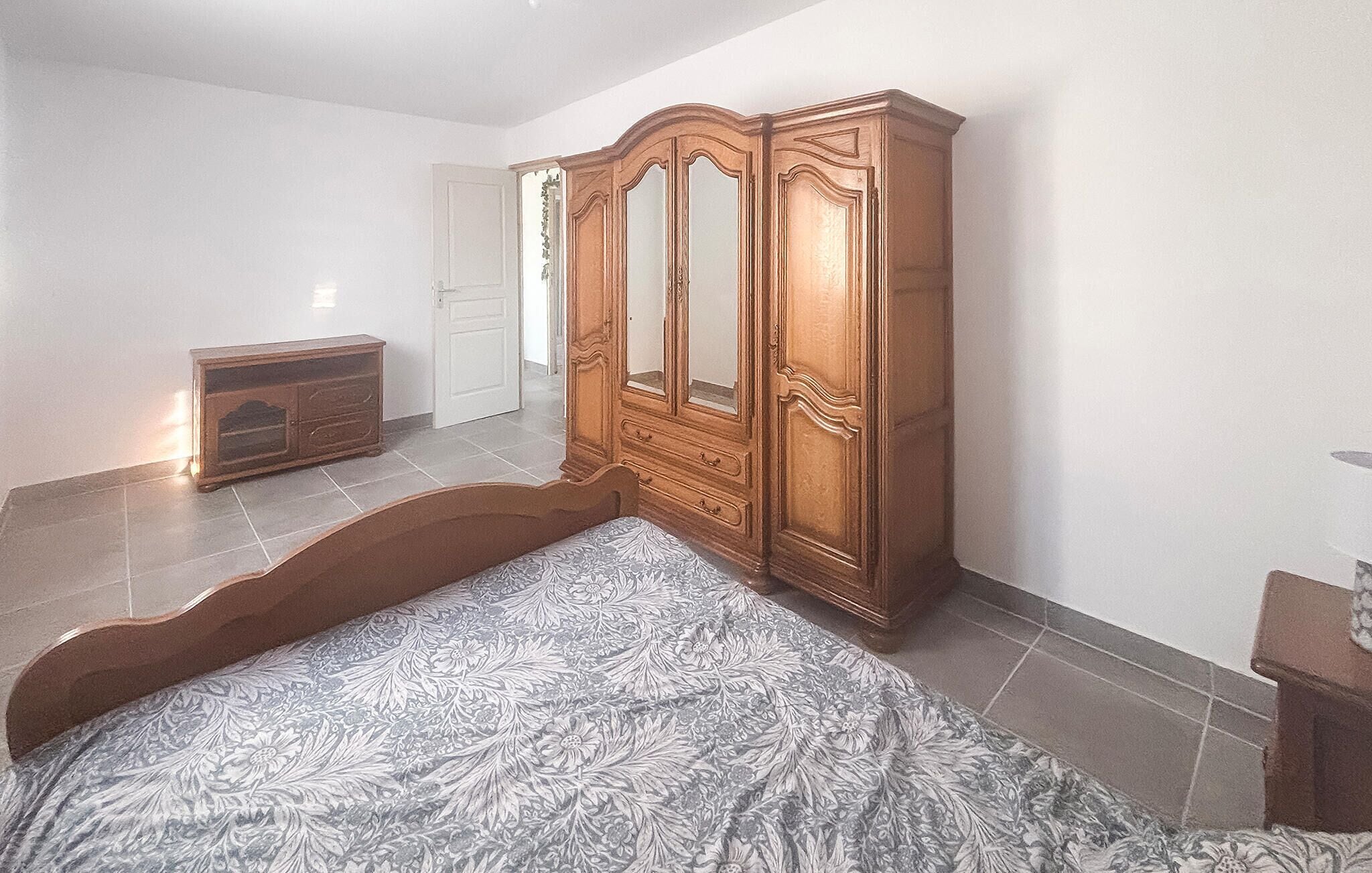 A bedroom with a bed, a wooden wardrobe, and a dresser.