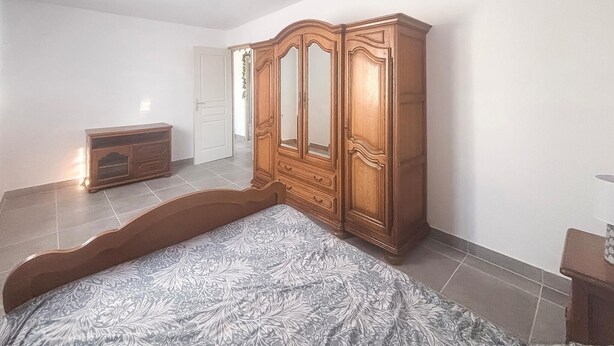 Un dormitorio con una cama, un armario de madera y un aparador.