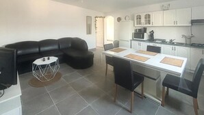 Un espacio habitable compacto con sofá, mesa de comedor, sillas y una zona de cocina.