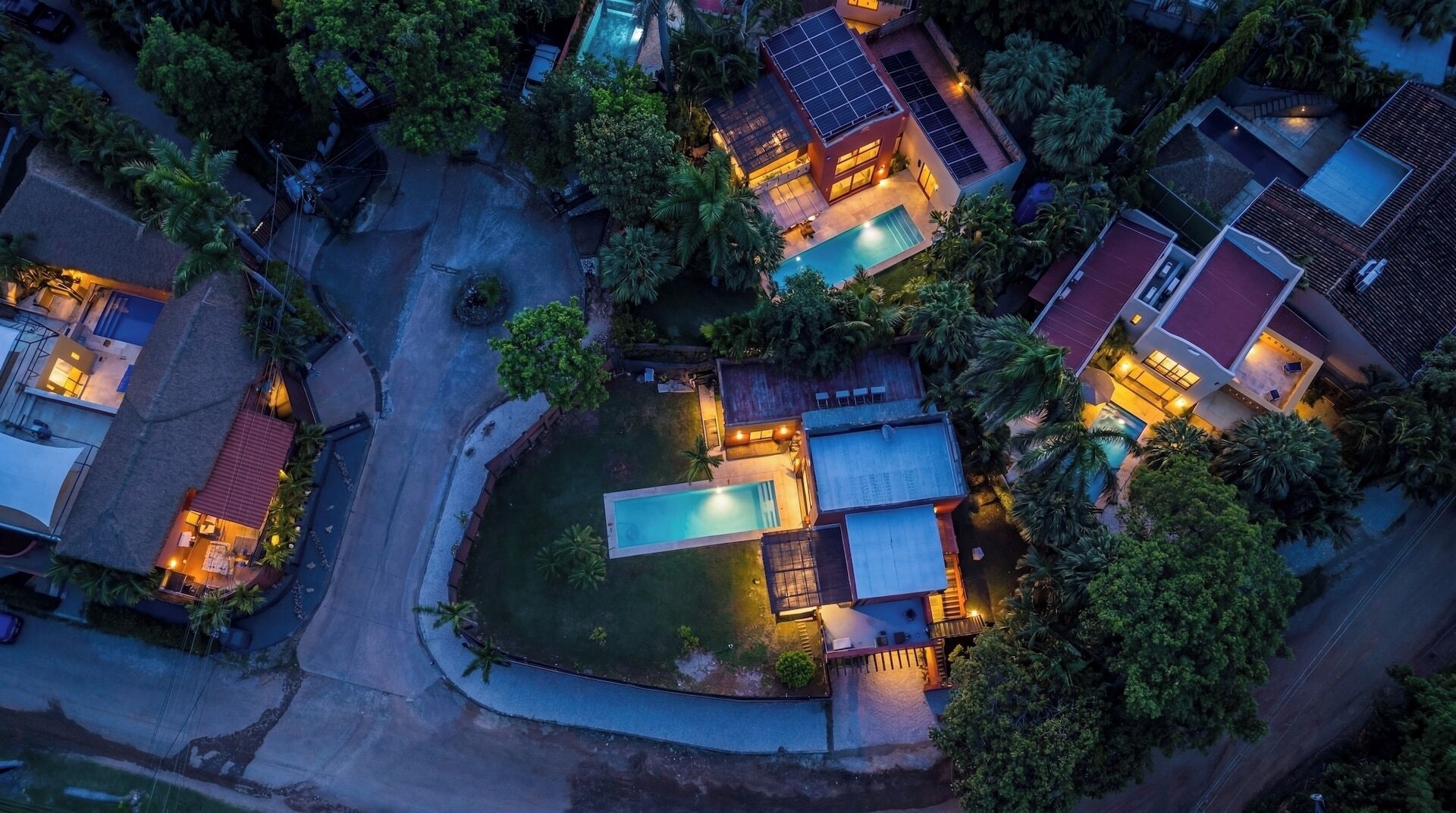 Vista aèria d'una zona residencial amb diverses cases, una piscina i panells solars.