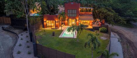 A modern house with a swimming pool, surrounded by a well-maintained lawn and palm trees.