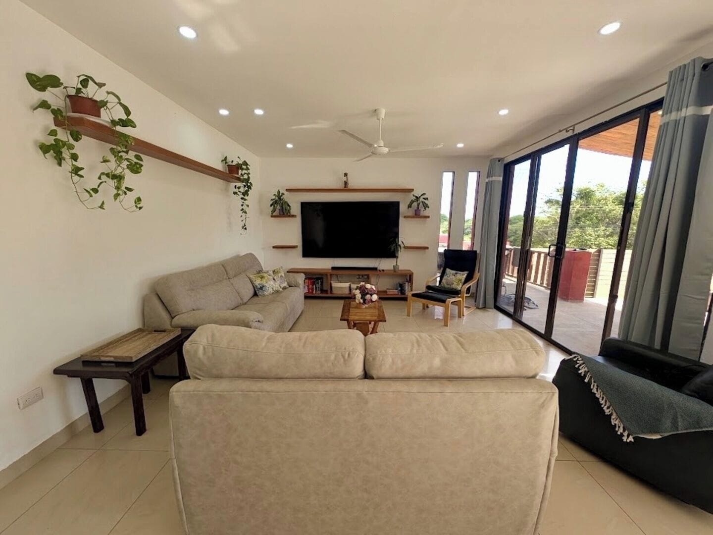 A living room with a sofa, a coffee table, a TV, and a balcony with a view.