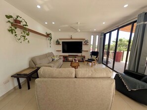 Un salon avec un canapé, une table basse, un téléviseur et un balcon offrant une vue agréable.