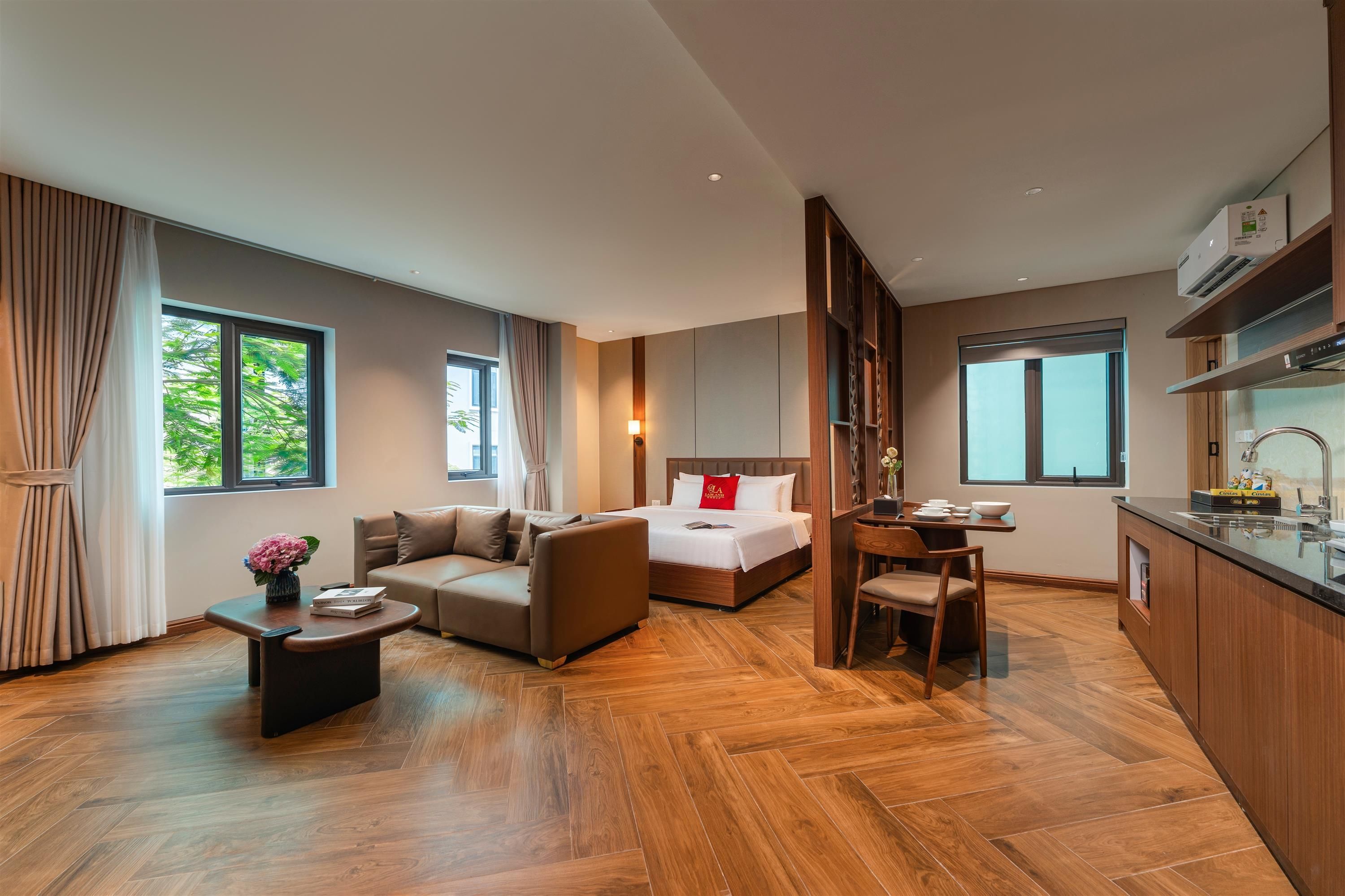 A modern hotel room with a sofa, a bed, a dining area, and a kitchen.