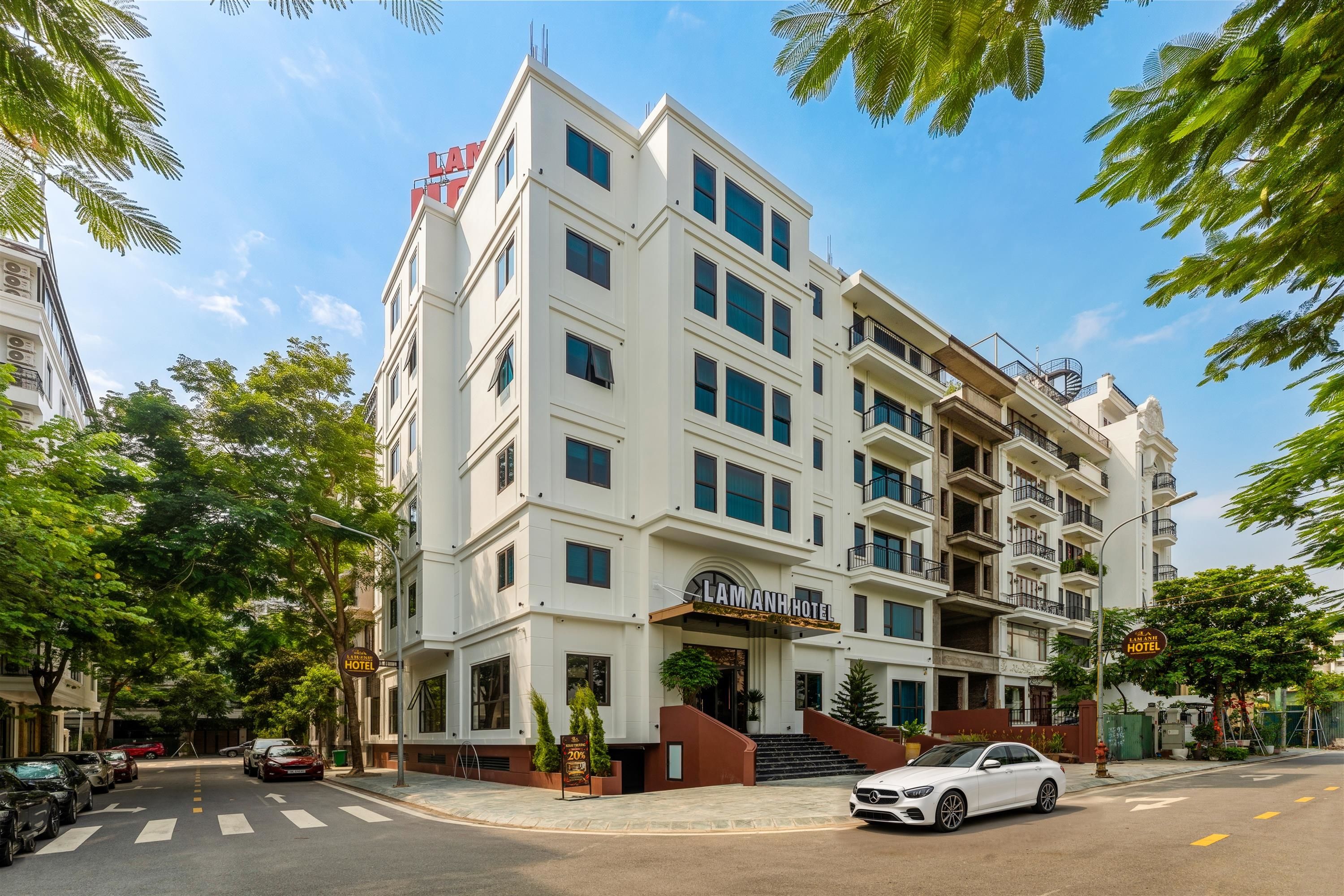 A multi-story hotel with a prominent entrance, a car parked in front, and a clear sky.