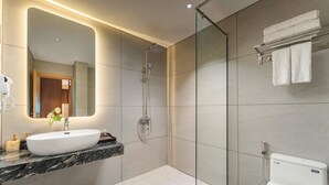 Uma casa de banho moderna com um espelho grande, uma sanita branca, um chuveiro e uma sanita.