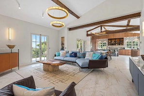A spacious living area with a sectional sofa, a coffee table, and a kitchen in the background. - Villa Shaily  300m Pampelonne Beach and Club 55 (Ramatuelle)