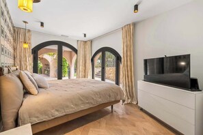 Ein Schlafzimmer mit einem Bett, einem Fernseher und Blick ins Freie.