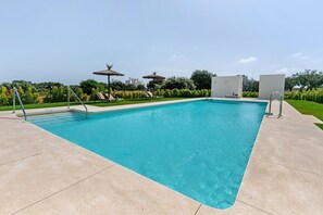 A rectangular swimming pool with a clear blue water surface, surrounded by a light-colored tiled deck.