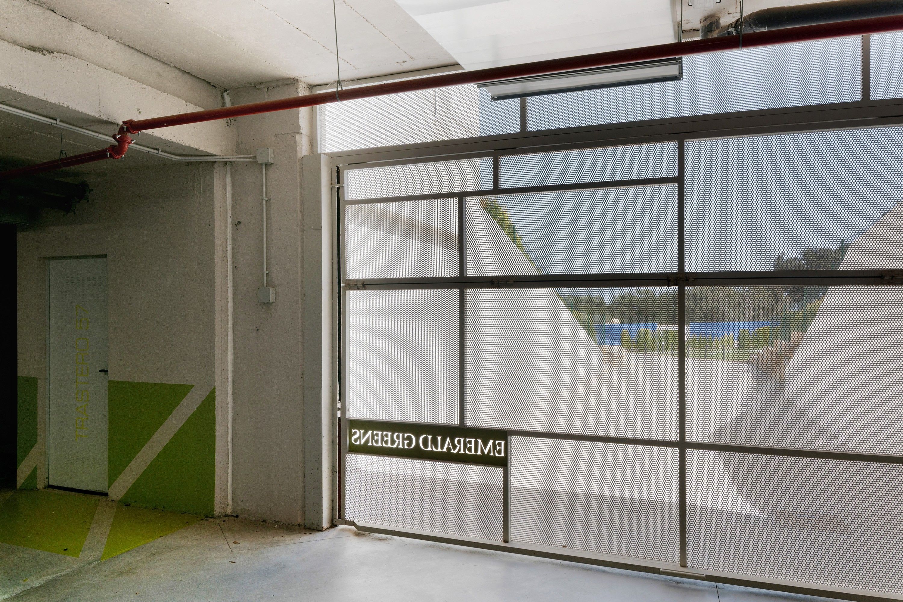Una habitación con un separador metálico, una puerta y un ventanal con vistas al exterior.