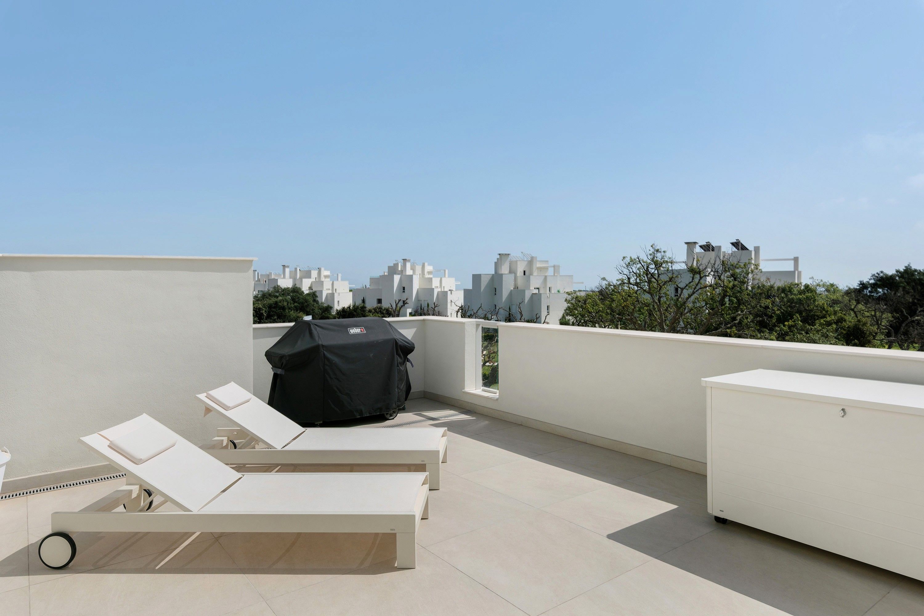 Una terraza en la azotea con sillones de descanso, una parrilla y vistas panorámicas de la ciudad.