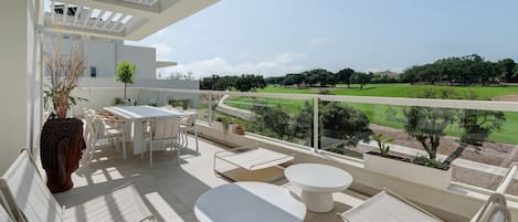 A balcony with a table and chairs, a round white table, and a Buddha statue.
