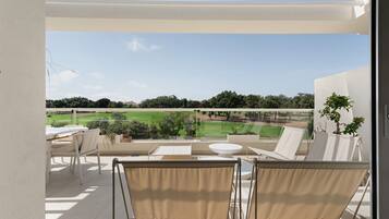 Un balcón con vista a un campo de golf, mobiliario exterior y una planta en maceta.