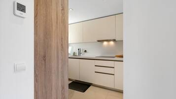Una cocina moderna con armarios blancos, encimera negra y estufa integrada.