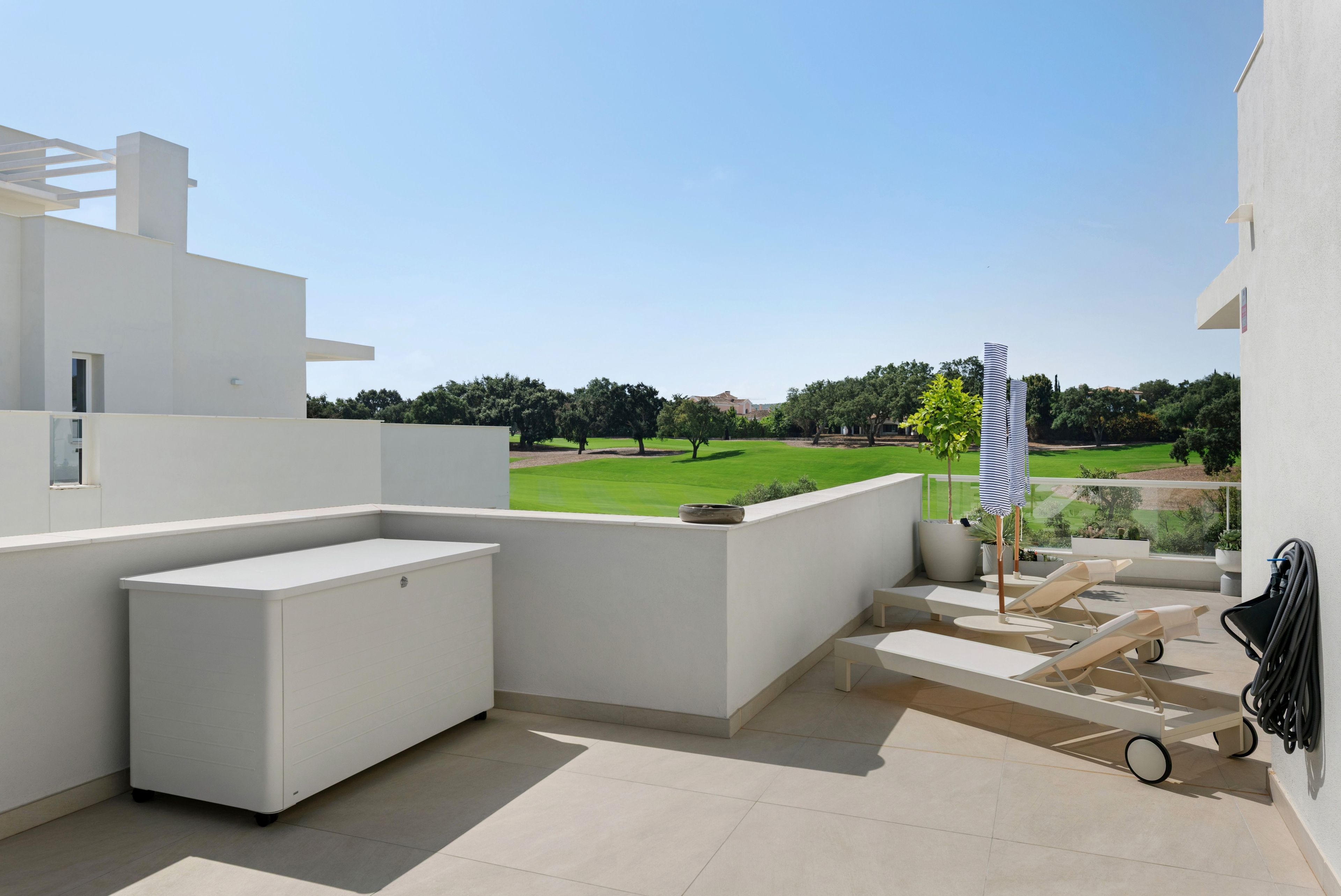 Una terraza moderna al aire libre con diseño minimalista, que incluye un banco integrado y vistas a un paisaje verde.