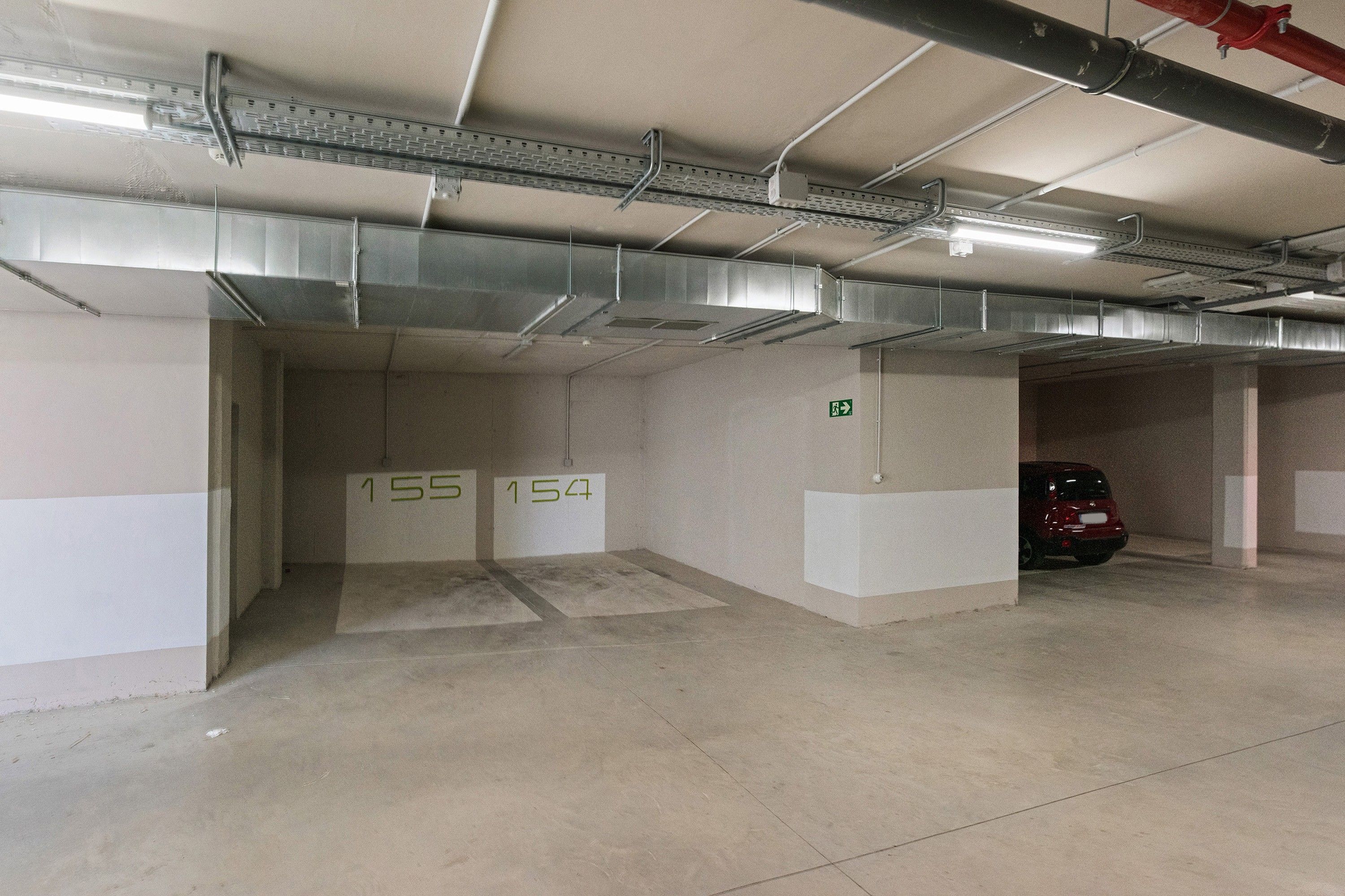 Eine Tiefgarage mit Betonwänden, nummerierten Parkfeldern und einem roten Auto in einem Feld.