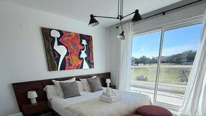 A modern bedroom with a large bed, a view of the outdoors, and a unique artwork on the wall. - Holiday Home 'Beautiful House in Emerald Green' with Sea View, Wi-Fi and Air Conditioning (San Roque)
