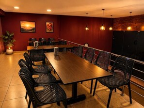 Un salón de conferencias con una larga mesa, sillas y un reloj en la pared.