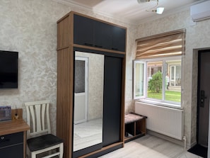 A room with a sliding wardrobe, a bench, a radiator, and a window with a view of the outside. - Enjoy Hotel (Tashkent)