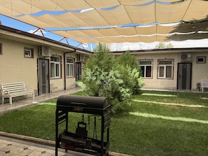 Un patio con una parrilla, un banco y un pequeño árbol.