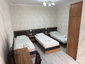 A hotel room with three beds, a wooden desk, and a wardrobe. - Enjoy Hotel (Tashkent)