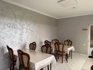 A dining room with a large table and chairs, a textured wall, and a door with a sign. - Enjoy Hotel (Tashkent)