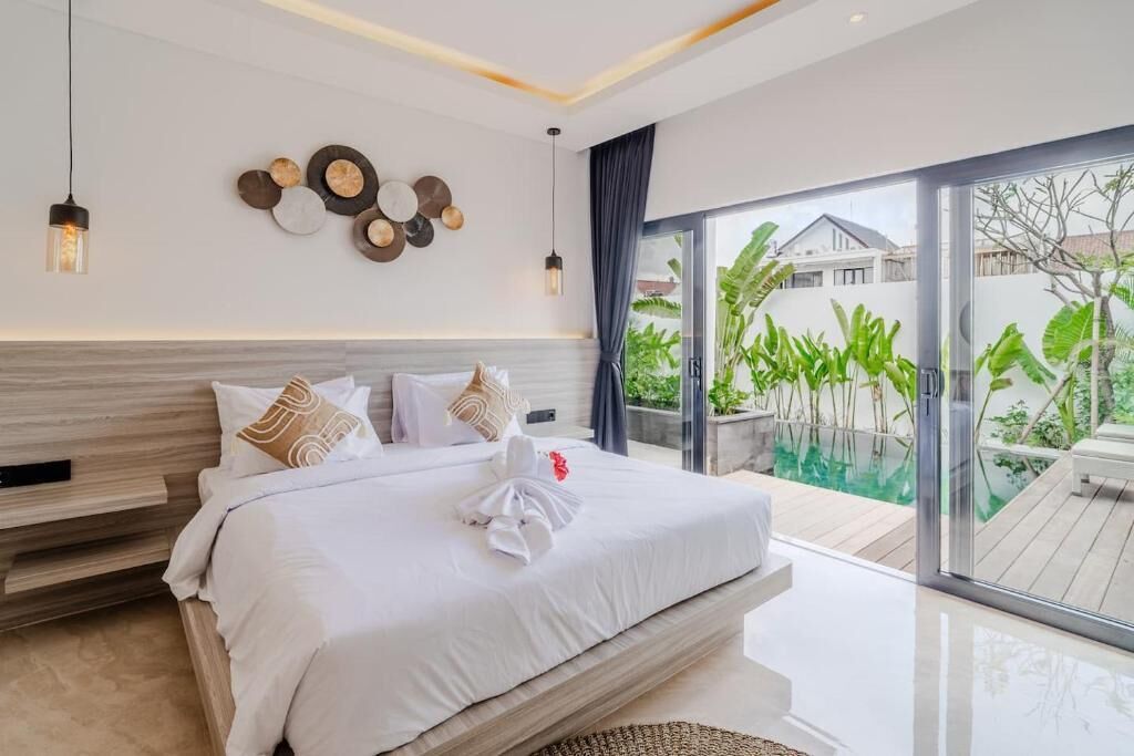 Een moderne slaapkamer met een groot bed, uitzicht op een zwembad en een balkon met planten.