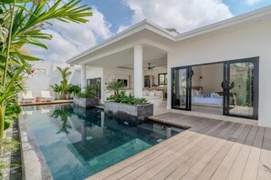 Een modern huis met een zwembad, terras en een slaapkamer met een groot raam.