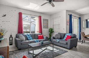 A living room with two grey sofas, a coffee table, and a ceiling fan. - 4BR Disney Getaway | Pool, Pirate & Castle Rooms (Davenport)