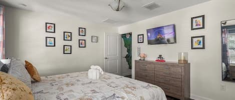 Ein Schlafzimmer mit Bett, Schminktisch und einem an der Wand befestigten Fernseher.