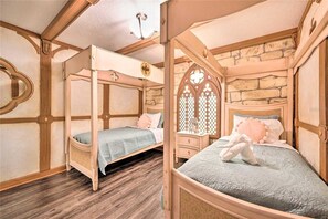Een slaapkamer met een hemelbed, nachtkastje, decoratieve spiegel en een stenen muur.