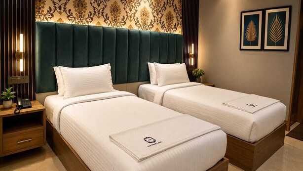 Ein Hotelzimmer mit zwei Betten, einem Holznachttisch, einem Telefon und einer Wand mit gerahmten Kunstwerken.