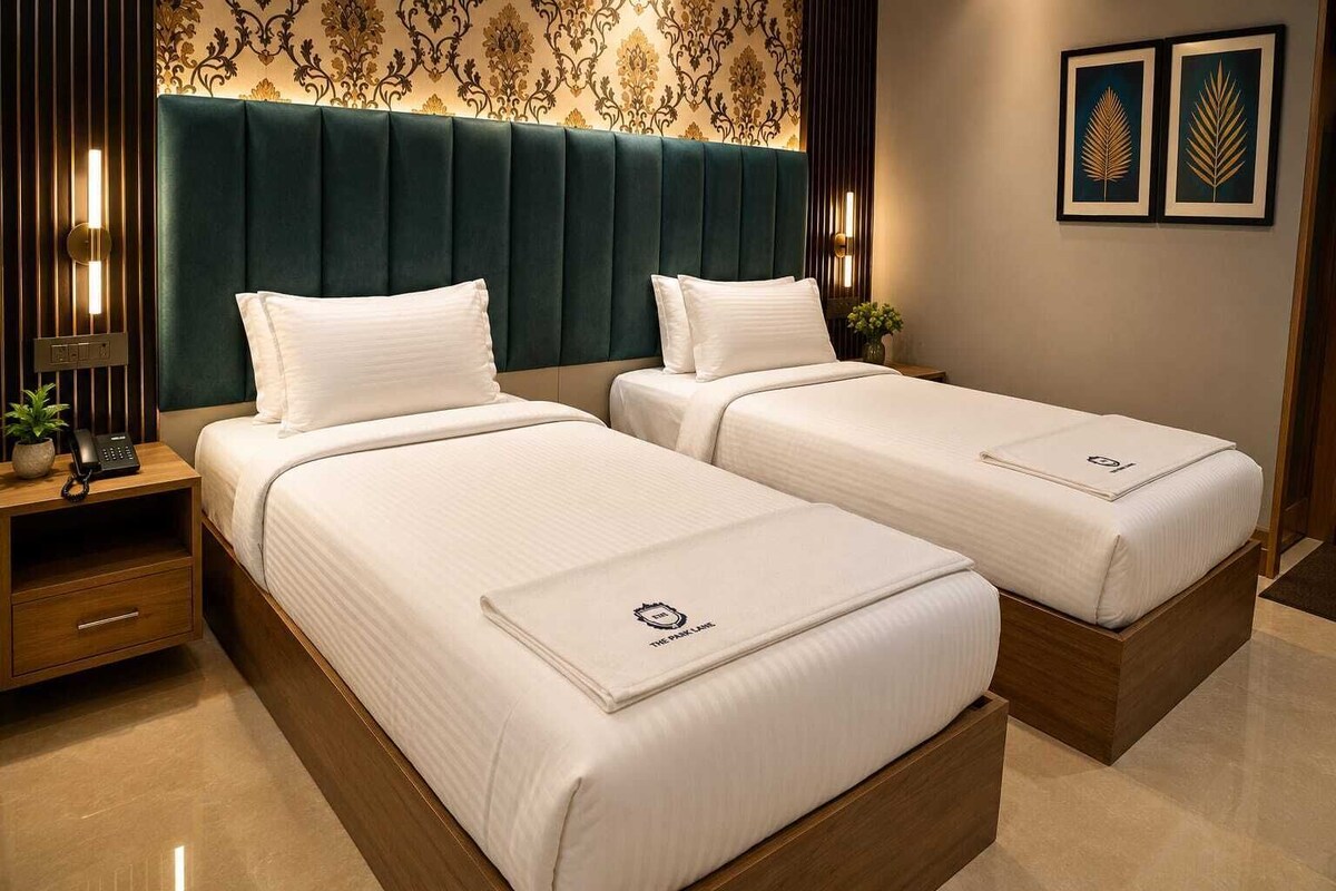 A hotel room with two beds, a wooden nightstand, a telephone, and a decorative wall with framed artwork.