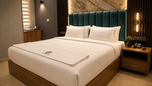 Ein Hotelzimmer mit einem großen Bett, einem Nachttisch aus Holz mit Telefon und einer Wand mit Marmoroptik.