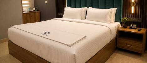 A hotel room with a large bed, a wooden nightstand with a telephone, and a marble-patterned wall.