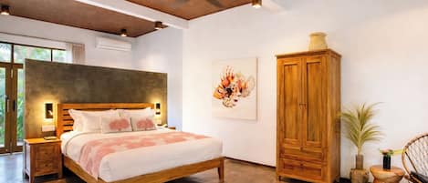 Un dormitorio con una cama grande, cabecera de madera, ventilador de techo y un armario de madera.