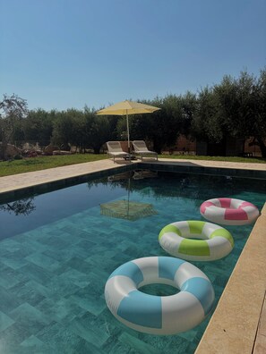 A clear swimming pool with lounge chairs and inflatable rings. - Terra Olive Hideaway 3 bedroom villa (Pegeia)