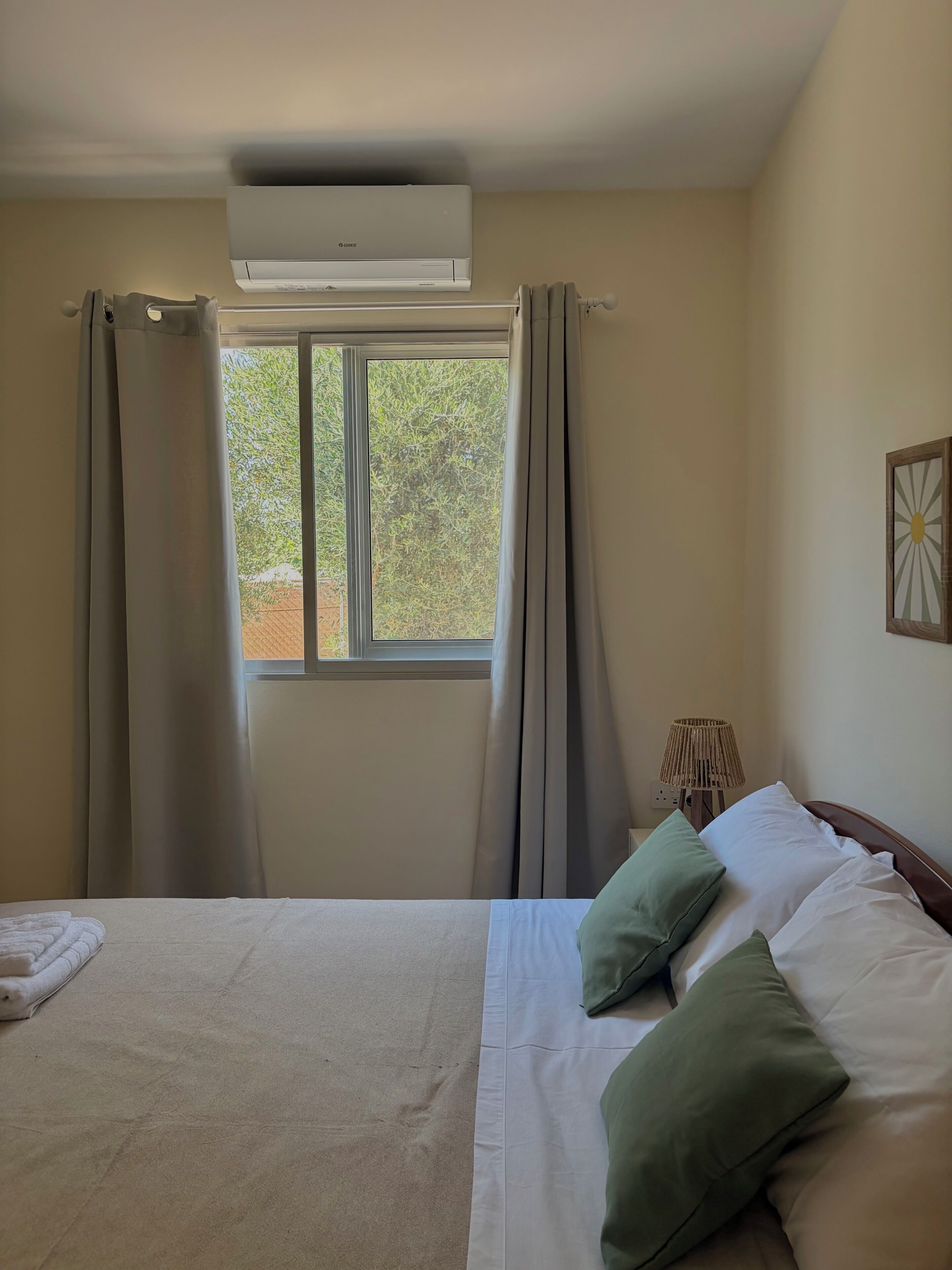 Ein Hotelzimmer mit Bett, einem Fenster mit Vorhängen, einer Klimaanlage und einer Lampe.