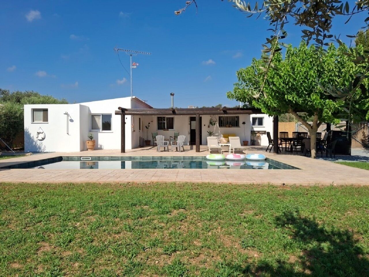 A modern house with a swimming pool, outdoor seating, and a well-maintained lawn.