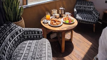 Un comedor con una mesa dispuesta para el desayuno, una planta en maceta y vista a un tren por la ventana.
