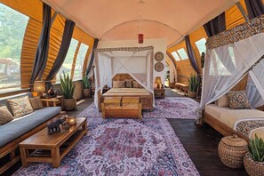 A tented accommodation with a central bed, two sofas, a dining area, and a view of the outdoors. - Africa Safari Manyara Migombani (mto wa mbu)