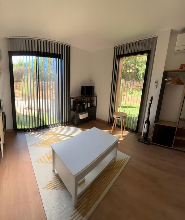 A modern living room with a white sofa, a TV stand, and a large window with curtains.