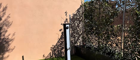 A garden area with a wooden deck, a metal post, and a wall.